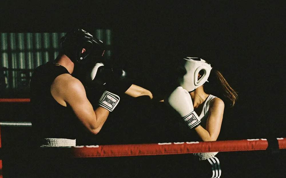 Two boxers sparring in headguards in a ring.