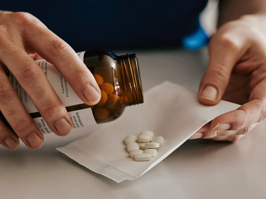 A nurse counting tablets from a bottle into a paper bag