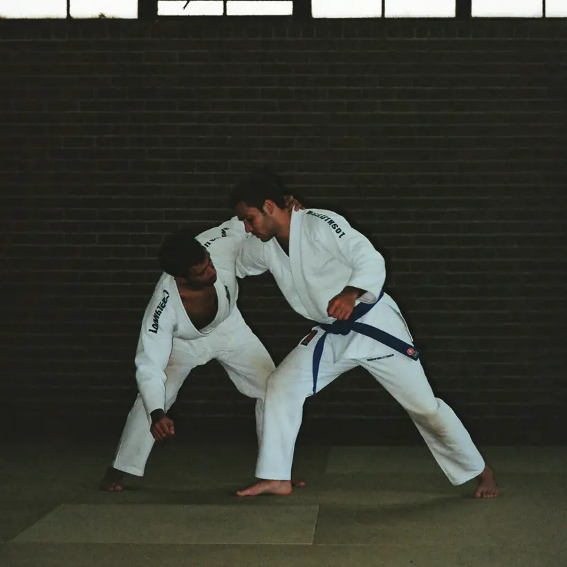 Two men grappling in gis on the mat