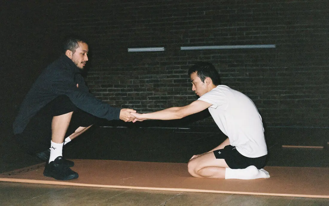 A coach giving one-to-one instruction to a student on the mat