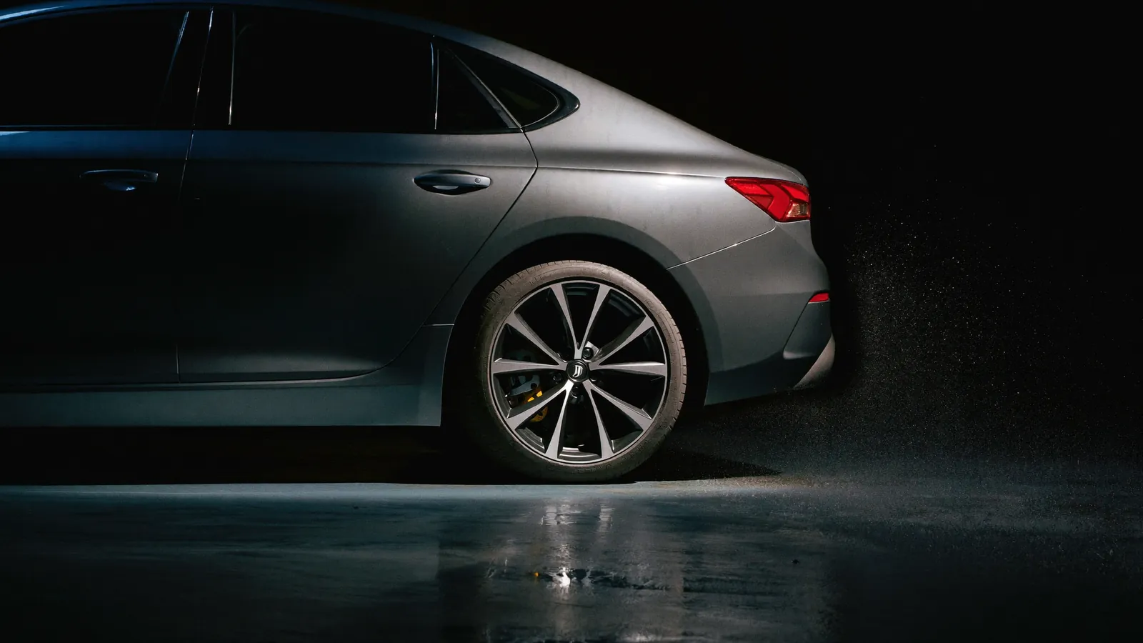The rear of a dark car in a dimly lit garage