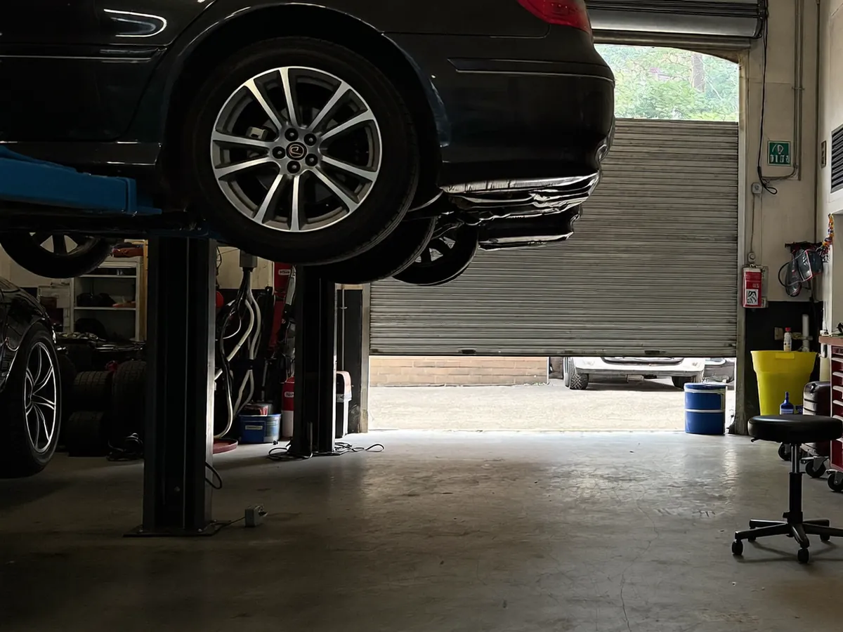 Two service bays with cars raised on lifts inside a tidy workshop