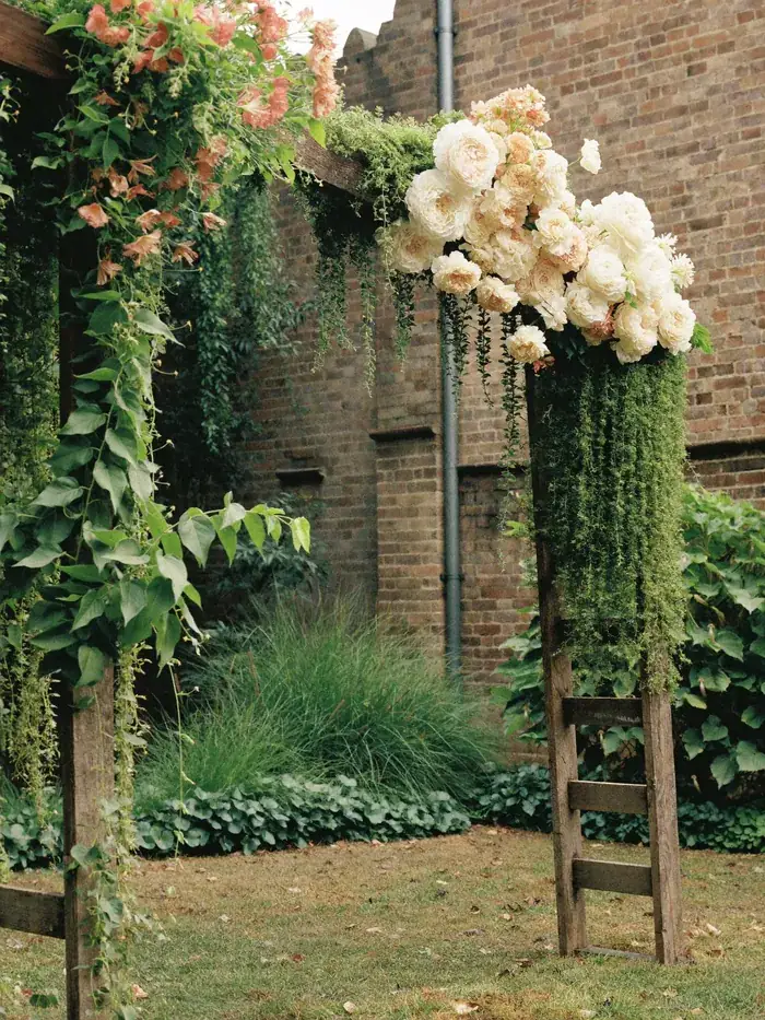 A timber wedding arch dressed with cream and blush flowers