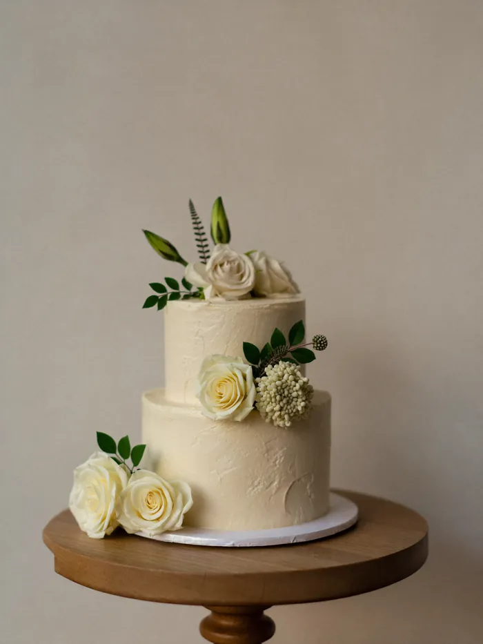 A two-tier naked wedding cake dressed with fresh flowers